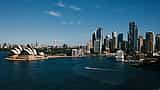 The Sydney skyline and Opera House viewed across the harbor on a clear sunny day.