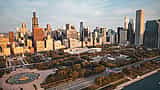 An aerial view of the Chicago skyline and Grant Park bathed in warm golden light.