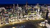 An expansive oil refinery brightly illuminated at night, showcasing the scale of modern energy infrastructure.