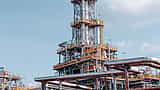 A bright daytime view of intricate pipelines and towers at a large oil refinery.