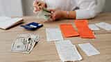 A person counts cash on a wooden desk scattered with shopping receipts and a blue calculator.