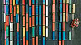 A top-down aerial view of vibrant, multi-colored shipping containers organized in neat rows at a logistics terminal.