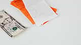 A U.S. five-dollar bill rests beside store receipts on a clean white surface.