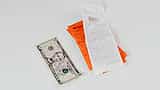 A five-dollar bill lies next to multiple printed shopping receipts on a light surface.