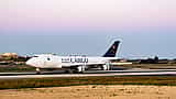A white Saudia Cargo airplane taxis on an airport runway at twilight.