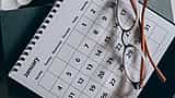 A close-up view of eyeglasses resting on a desk calendar.