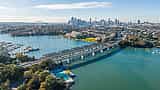 An aerial view of the Sydney skyline, harbor, and bridges on a bright sunny day.
