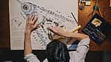An overhead view of an architect using a compass and ruler to measure a detailed site blueprint.
