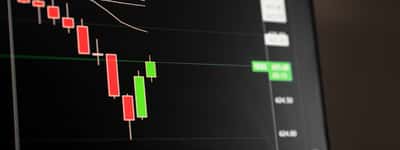 A digital financial screen showing a downward market trend with red candlestick charts.