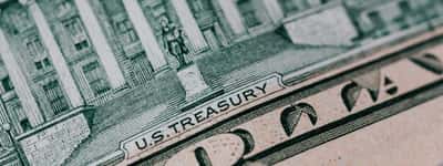 A macro close-up of the back of a U.S. ten-dollar bill showing the U.S. Treasury building and engraving.
