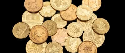 A collection of various gold investment coins resting against a black background.