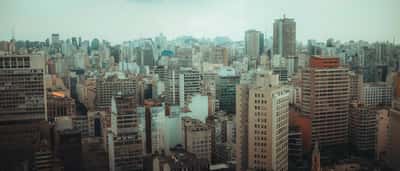 A dense urban skyline with modern high-rises and busy elevated highways in São Paulo, Brazil.
