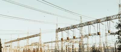 A complex electrical substation with numerous metal towers and power lines against a clear sky.