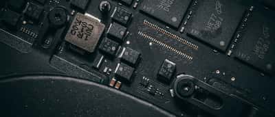 A close-up view of microchips and electronic components on a dark computer circuit board.