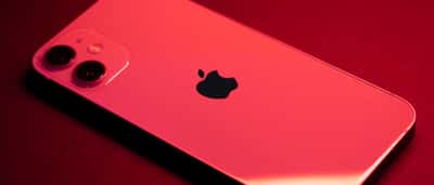 An iPhone bathed in deep red light, displaying the Apple logo on its back.