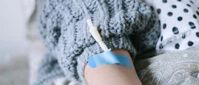 A close-up of a patient wearing a knitted sweater receiving an intravenous drip.