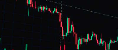 A digital financial chart displaying a sharp downward trend with red candlestick patterns against a dark grid.
