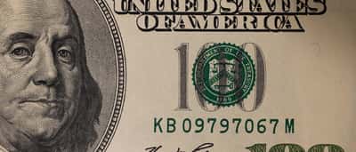 A detailed macro photograph of a US one-hundred dollar bill highlighting the Department of the Treasury seal.