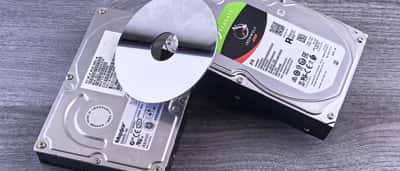 A Seagate hard drive and a silver disk platter resting on a dark wooden surface.