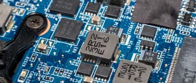 A close-up view of a green electronic circuit board showing intricate metallic pathways and microchips.