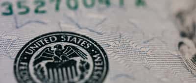 A close-up view of the United States Federal Reserve System seal printed on a dollar bill.