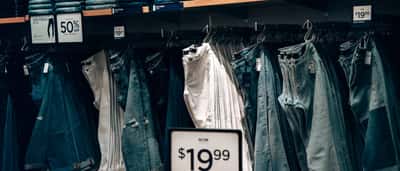 A retail display of denim jeans featuring clear price tags and discount signs.