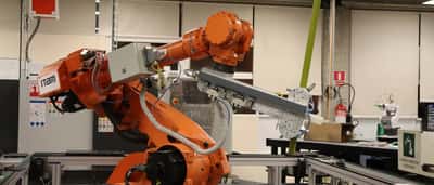 A yellow industrial robotic arm operates within a modern manufacturing or laboratory setting.
