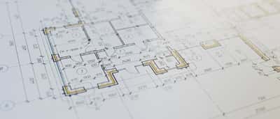 A close-up view of an architectural blueprint and floor plan with highlighted sections.