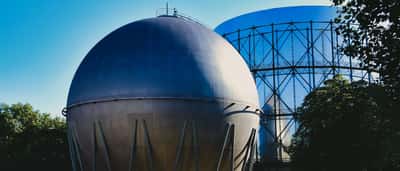 A massive spherical industrial gas storage tank standing against a clear blue sky.