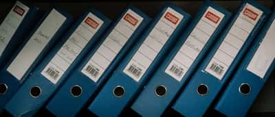 A row of uniform blue document binders arranged neatly on a shelf.