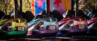 Three brightly colored bumper cars with thick rubber rims lined up side-by-side.