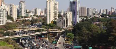 An aerial view of the urban skyline and a bustling expressway in São Paulo, Brazil.