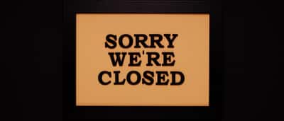 A framed sign reading 'Sorry we're closed' against a dark background.