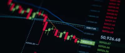 A digital stock market chart displaying a sharp downward trend with red candlesticks on a dark screen.