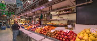 A bustling fruit stall in a Spanish market displaying fresh apples and pears with clear price tags.