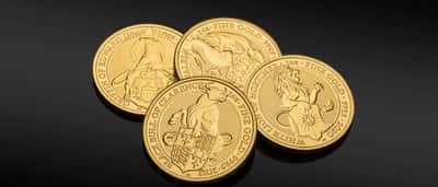 Three one-ounce fine gold coins resting on a dark reflective surface.