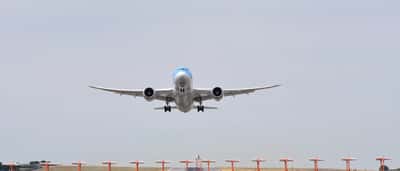 A large passenger airplane lifts off the runway into a clear sky.