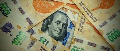 A US hundred-dollar bill surrounded by an arrangement of Argentine thousand-peso banknotes.
