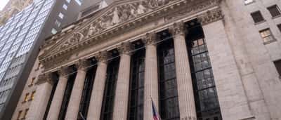 The classic stone facade and columns of the New York Stock Exchange building seen from a low angle.