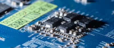 A detailed macro shot of microchips and electronic components on a blue circuit board.