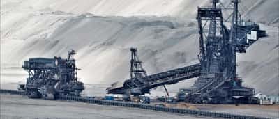 Giant bucket wheel excavators operate in a massive, dusty open-pit mine.