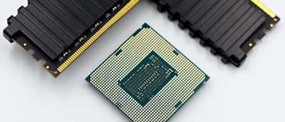 A computer processor and several black RAM sticks rest on a white surface.