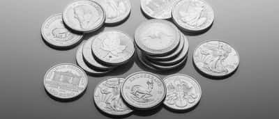 A collection of pristine silver bullion coins resting on a smooth, reflective surface.