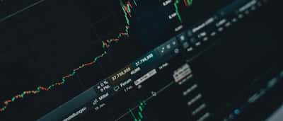 Close-up of a digital stock market trading screen displaying illuminated financial charts and data.