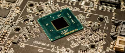 A close-up view of a central microchip on a warm, illuminated computer circuit board.