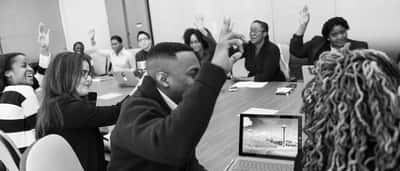 Professionals raise their hands to vote during a corporate boardroom meeting.