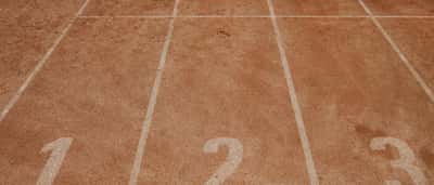 A vibrant red running track with bright white lane markers.