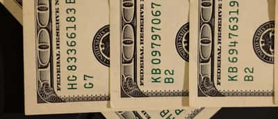 A close-up view of U.S. dollar bills highlighting the Federal Reserve seal and serial numbers.