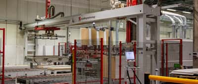 A large automated material handling machine operates on a production line inside a modern factory.