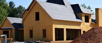 A wooden residential house with exposed framing and sheathing under construction.